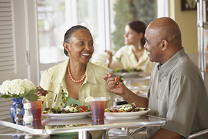 Man and woman sitting in restaurant eating salads.