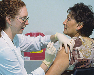 Mujer madura recibiendo una inyección en la parte superior del brazo.